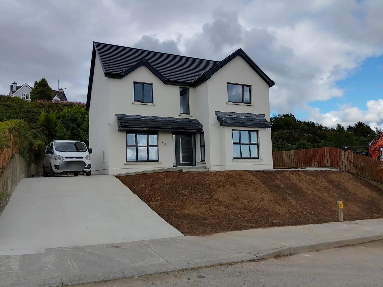 Finished two storey new build with white render, dark roof tiles and dark window frames