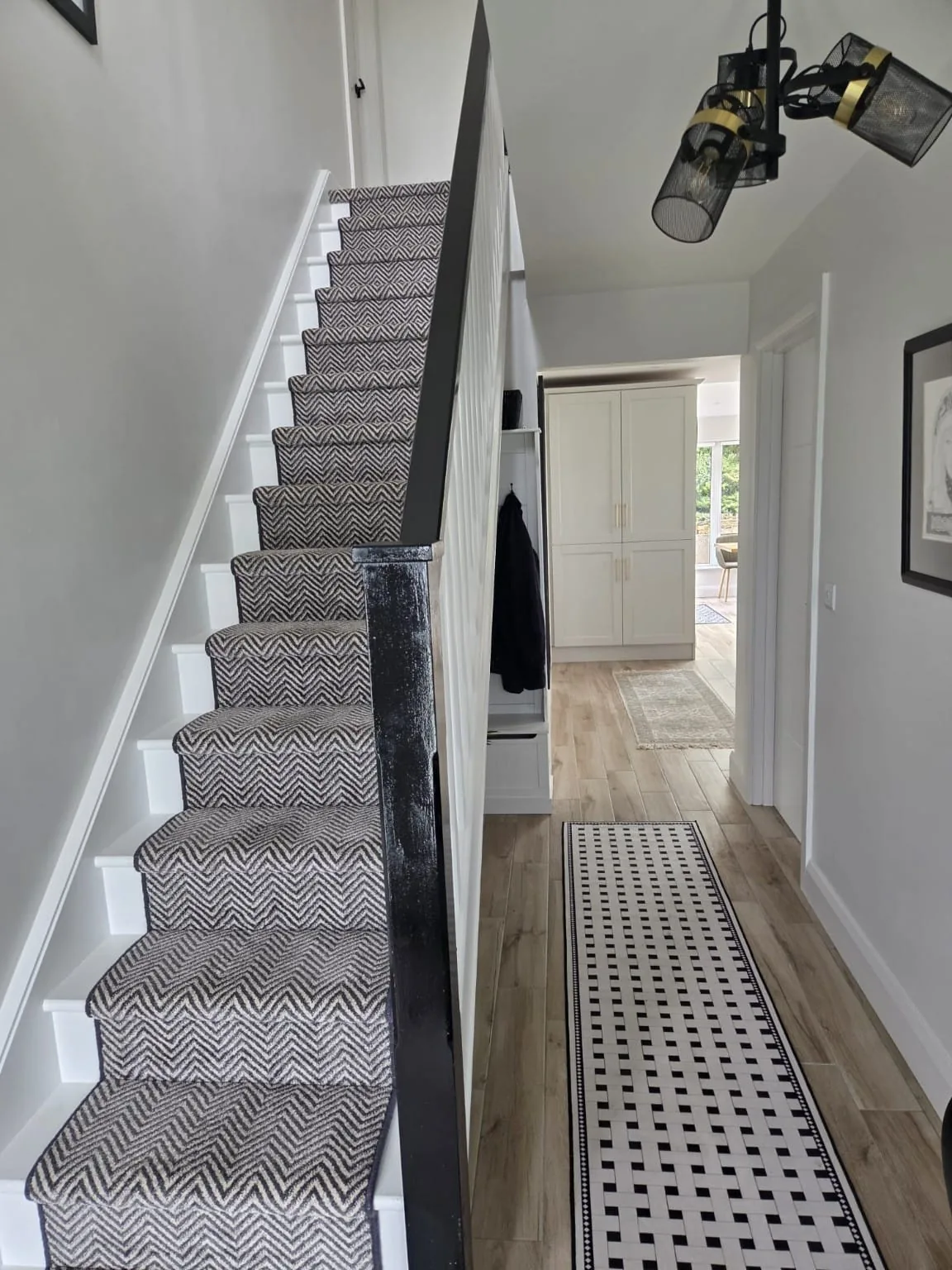 White staircase with a black handrail and patterned runner