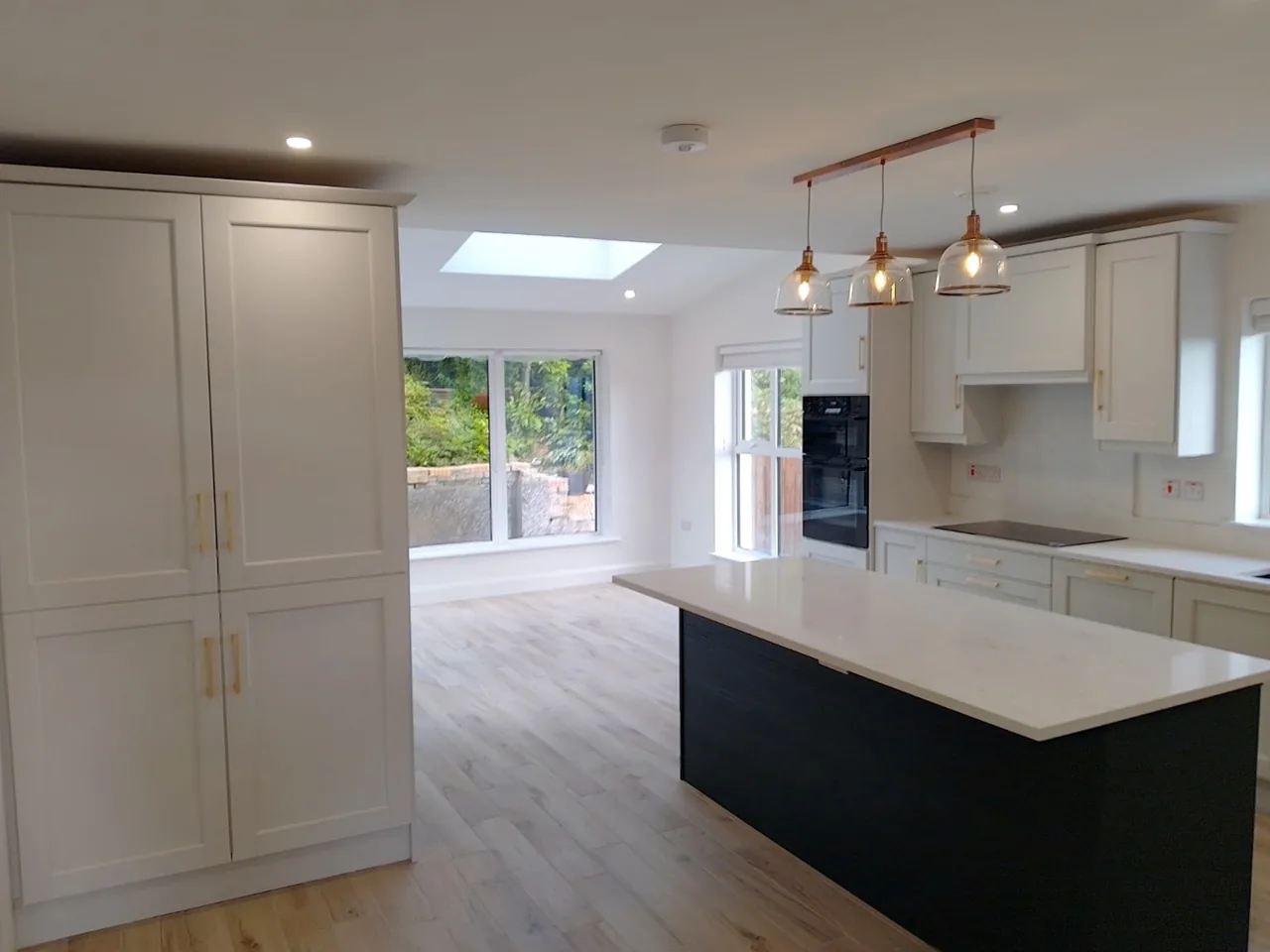 Finished kitchen with island, rooflight and pendant lights at handover